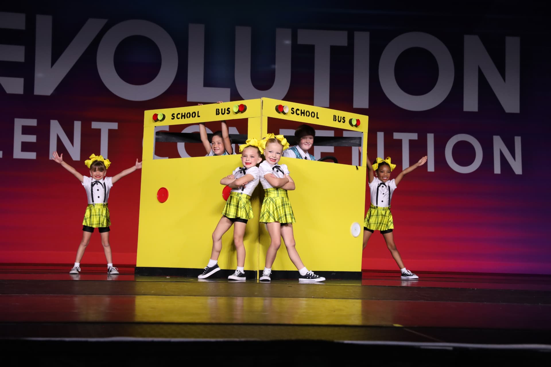 Young dancers performing with a bright yellow school bus prop
