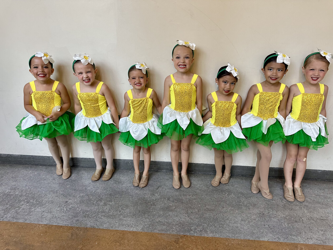 Seven young MSDC dancers in yellow and green flower costumes backstage